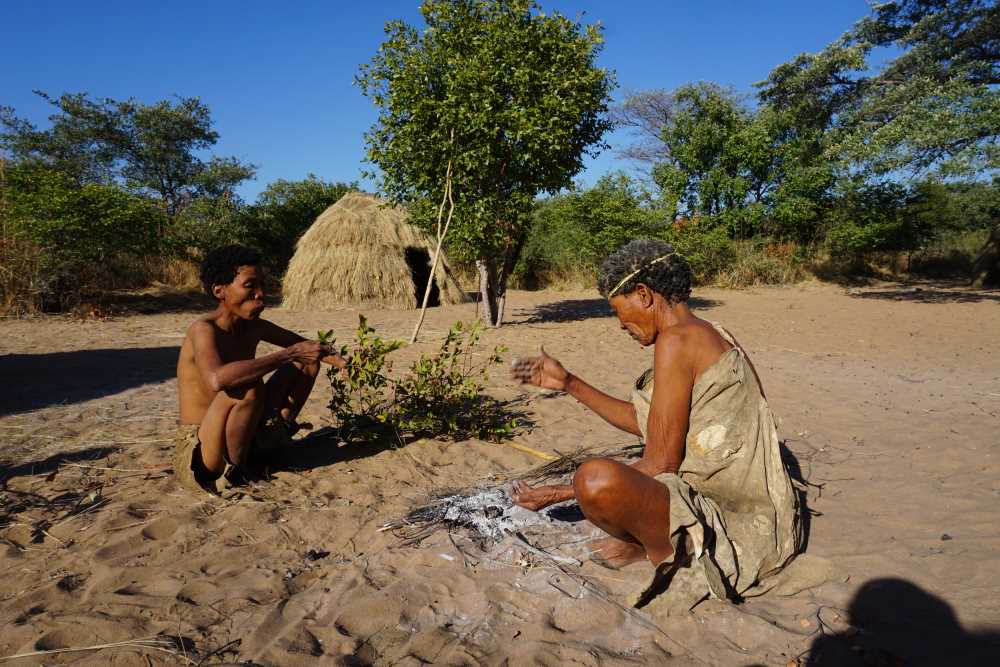 Buschmänner, die in ihrem Dorf Sandpapier-Rosinen essen